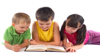 Three children on floor reading a book